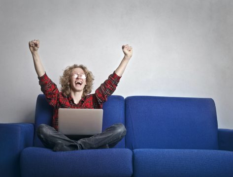 photo-of-excited-person-with-hands-up-sitting-on-a-blue-sofa-3770000
